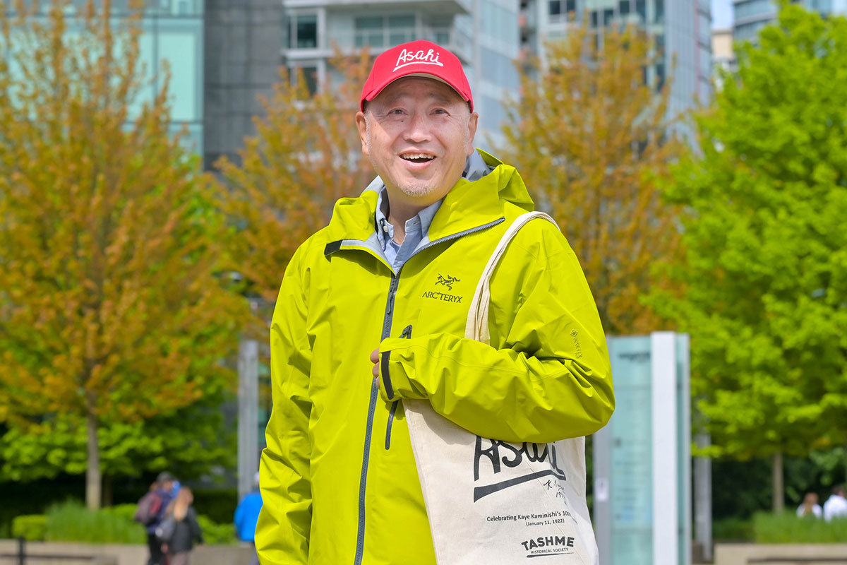 バンクーバーの野球チーム “Asahi”のロゴが入った帽子と布製バッグで、笑顔を見せる原田監督。2022年5月29日。Photo by Saito Koichi